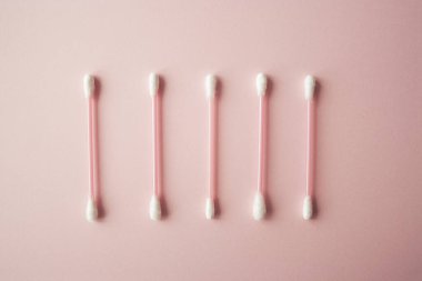 Pembe, sıcak arka planda düz pamuk tomurcukları vardı. Pamuklu çubuklar, güzellik ve sağlık hizmetleri konsepti. Pamuk bileşimi