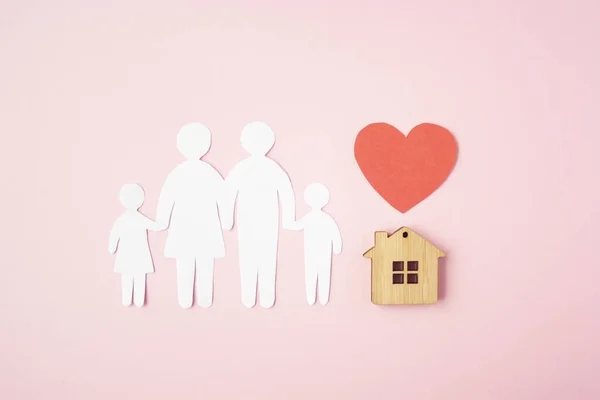 Happy paper family with house and red heart on pink background. Love and family union concept.