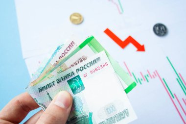 Rus rublesi ve kırmızı ok döviz kurunda rubleyi tutan erkek el. Ruble değer kaybı. Karşılıklı düşüş oranı. Dolara dönüş