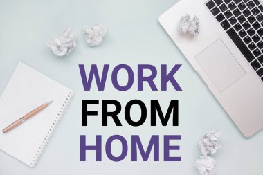 Ev kavramından çalış. Dizüstü bilgisayar, not defteri, buruşmuş kağıt ve kalem üst görünümü fotokopi alanı olan düz bir fotoğraf. Coronavirüsü durdurmak için evde kal.