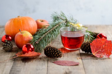 Beyaz ahşap zemin üzerinde Noel köknar ağacı dalı ve bitkisel çay oyuncaklar, kabak, elma ve sonbahar yaprakları