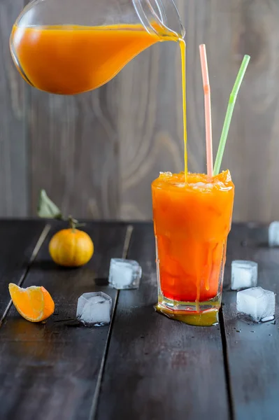 Bebida de coquetel laranja fresca com cubos de gelo em fundo de madeira preta — Fotografia de Stock