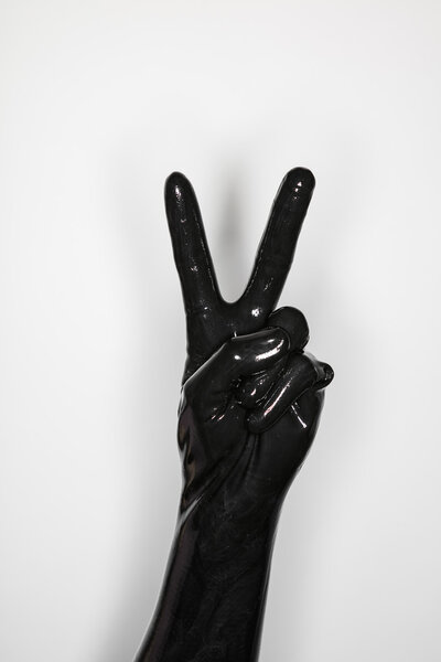 gesture of a hand wearing a black latex glove, victory sign