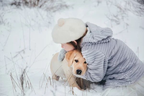 Dziewczyna bawi się śnieg w lesie z pies Labrador — Zdjęcie stockowe