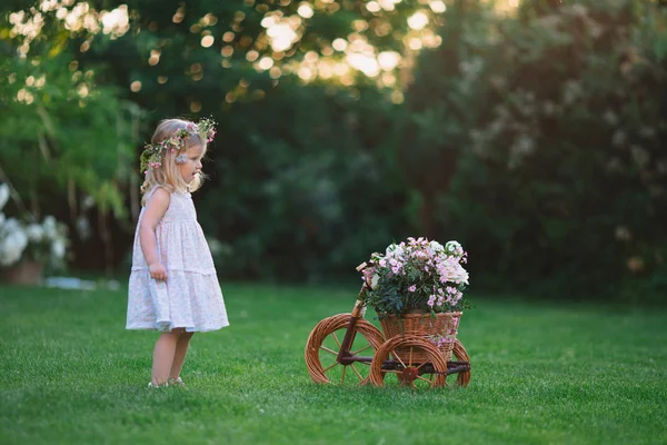 Flicka som leker på gräsmattan med blommor — Stockfoto