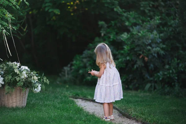 Flicka som leker på gräsmattan med blommor — Stockfoto