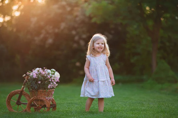 Mädchen spielt auf dem Rasen mit Blumen — Stockfoto