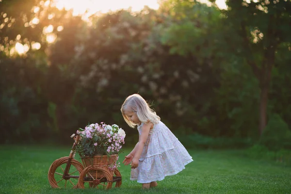 Fille jouer sur la pelouse avec des fleurs — Photo