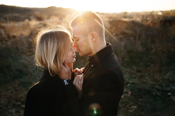 Side view portrait of two young lovers kissing on the sunset