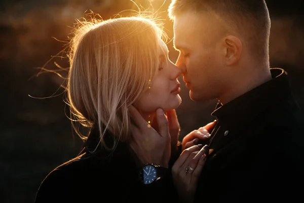 ภาพด้านข้างของคู่รักหนุ่มสาวสองคนจูบกันตอนพระอาทิตย์ตก รูปภาพสต็อก