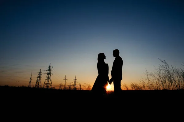 Silhouette of Couple ölelés elektromos vezetékek háttérben naplementekor. Mentsd meg a bolygót és az elektromosságot. Emberség és elektromosság. Energiaelosztó hálózat - Villamos oszlopok. Az Eiffel-torony — Stock Fotó