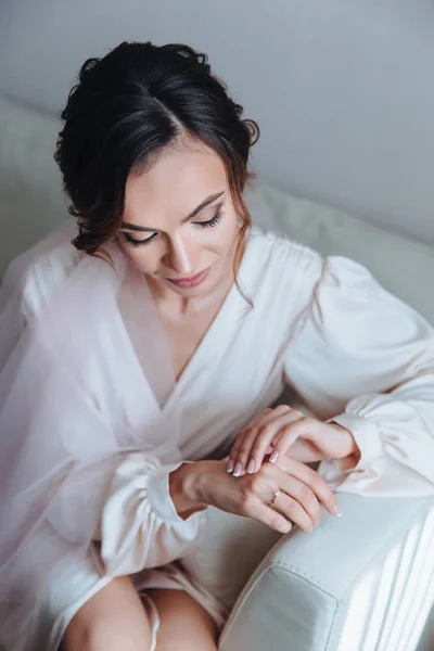 เจ้าสาวตอนเช้า เจ้าสาวที่สวยงามกําลังรองานแต่งงาน นั่งอยู่บนโซฟาในห้องสีขาว ผู้หญิงในชุดแต่งงาน โพสบนโซฟา — ภาพถ่ายสต็อก