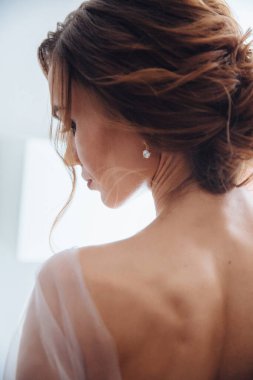 Gelinin portresini arkadan açık elbiseyle kapat. Elbisenin yakası çok güzel ve gelinin arkası çok seksi. Arka plan