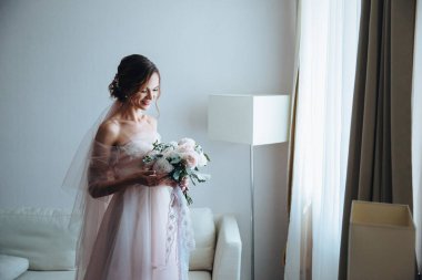 Güzel pembe ve beyaz şakayıklar ve yeşil narin düğün buketi gelinin ellerinde. Yan görünüm