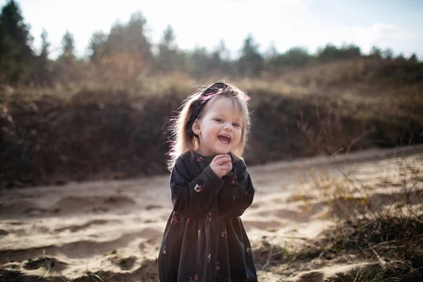 Nära porträtt av söt liten skrattande flicka poserar framför kameran i höstskogen. — Stockfoto