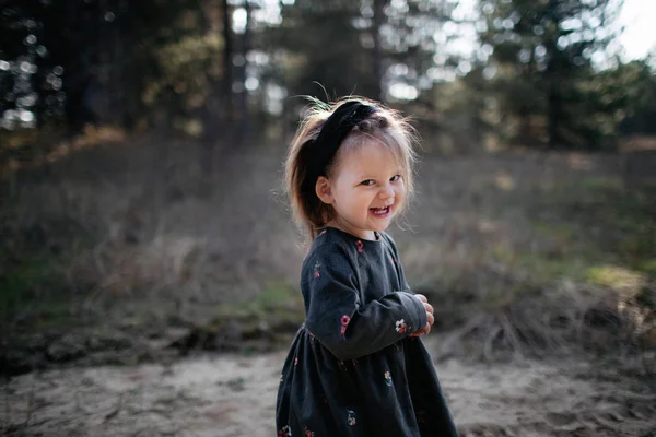 Nära porträtt av söt liten leende flicka poserar framför kameran i höstskogen. — Stockfoto