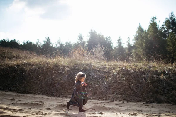 Gadis kecil yang lucu tersenyum berlari di hutan musim gugur. Pembangkangan. Kebahagiaan. Tampilan samping Stok Lukisan  