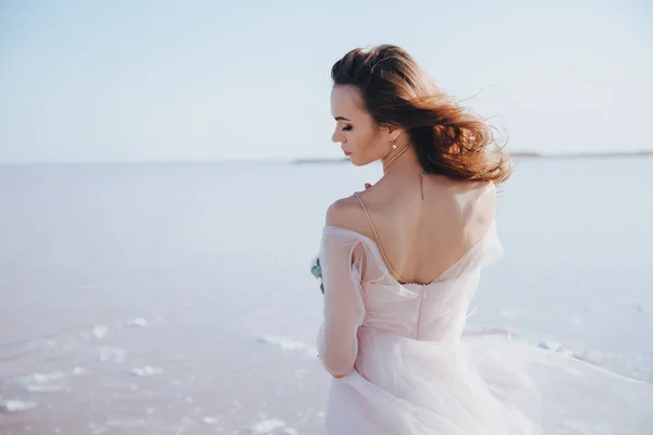 Noiva sensual em um vestido de noiva na praia. Visão traseira . — Fotografia de Stock