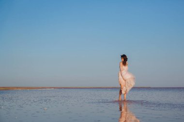 Uçan gelinlik içindeki şehvetli gelin saçlarında rüzgarla deniz kıyısına asmış. ön görünüm