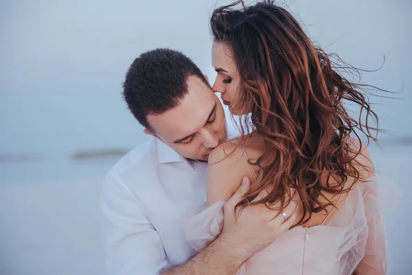 Atractivos recién casados en la orilla del mar. Hombro de novia besucona. vista lateral y trasera —  Fotos de Stock