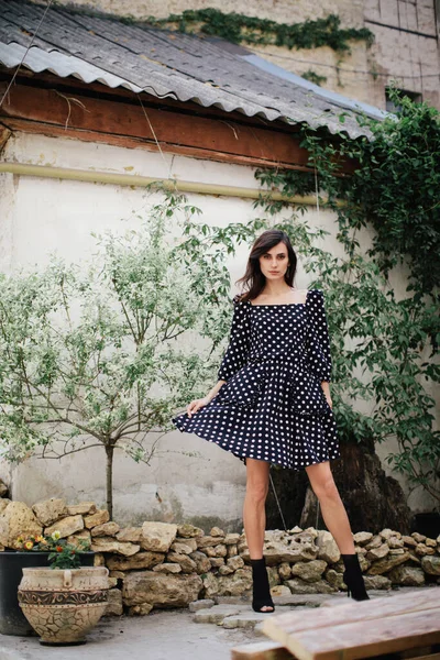 Mooi brunette Model in polka-dot zwart-wit jurk poseren op camera op lentedag Rechtenvrije Stockafbeeldingen