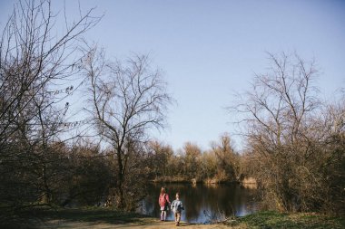 Small kids girl and boy are looking to the water on the river bank at sunset. Family time together.