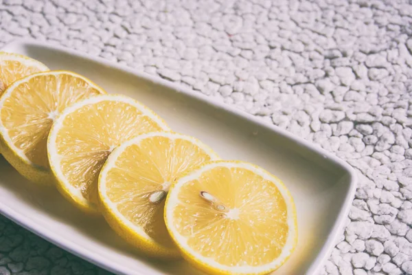 Λεμόνι σε ένα άσπρο πιάτο, κόβουμε κύκλους από λεμόνι — Φωτογραφία Αρχείου