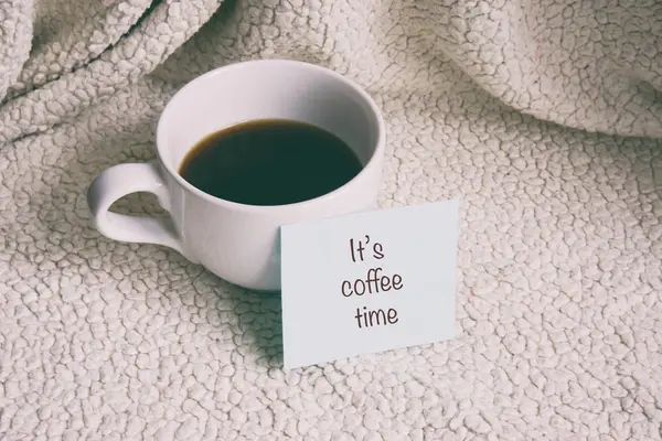 Una taza de café, una nota cerca de la taza, la taza en un fondo blanco —  Fotos de Stock