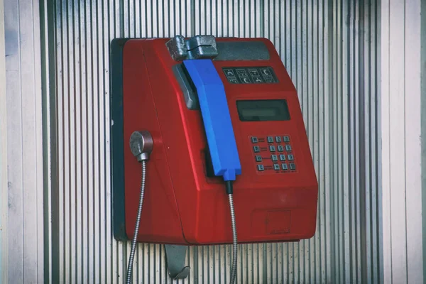 Telefone público vermelho com um tubo azul está em uma cabana de alumínio — Fotografia de Stock
