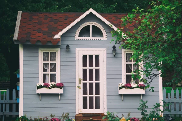 small gray house with flowers and a white door