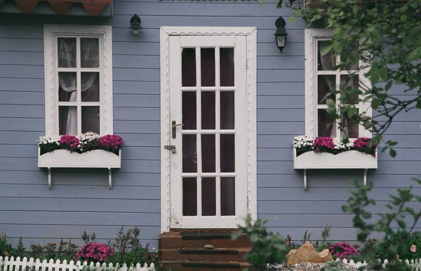 çiçek ve beyaz bir kapı ile küçük gri ev