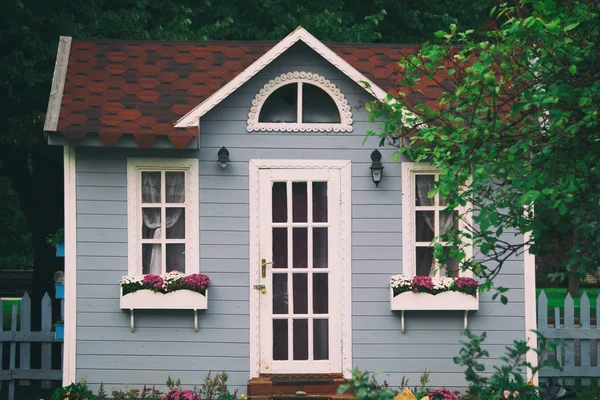 Маленький сірий будинок з квітами і білими дверима Ліцензійні Стокові Зображення