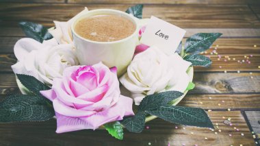 Ahşap bir masa bir tabağa, kağıt üzerinde bir not gül çiçek