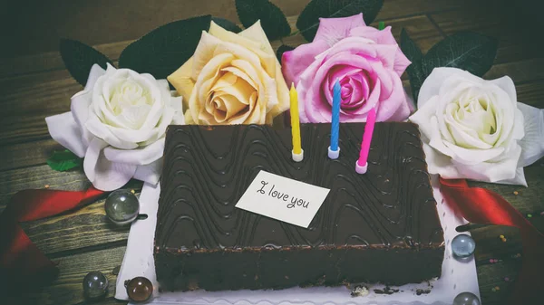 Gâteau d'anniversaire avec des bougies et des fleurs, une note sur le papier — Photo