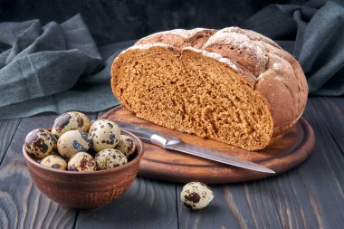 Çavdar ekmeği. Çavdar unu ve tam çavdar tanesinden yapılmış ekmek. Kil kasede bıldırcın yumurtası, ekmek bıçağı. Kırsal stil, ahşap kesim tahtası, keten, çam ağacı. Taze, sağlıklı çiftlik yemekleri..