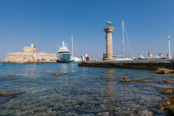 Άγαλμα ελάφια και κυνηγόσκυλο και στήλες στο Μανδράκι. Σε φόντο φρούριο Santa Claus. Τόπος όπου υπήρχε άγαλμα, Κολοσσός της Ρόδου. Συμβολική πύλη του λιμανιού. — Φωτογραφία Αρχείου