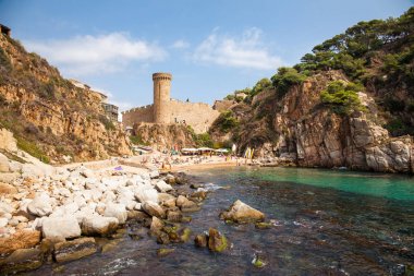 Tossa de mar, view of the castle tower and city walls. Fortress on the beach side. Blue lagoon and steep cliffs. clipart