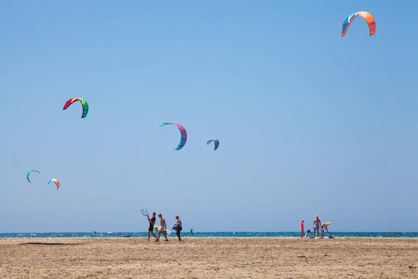 People practicing Kitesurfing. Beach on the peninsula Prasonisi, Rhodes. Colorful kites on the sea shore. Blue sea and windsurfing.