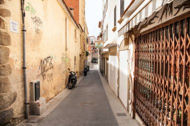Homes near the narrow streets of Lloret de Mar. Downtown of Lloret, Spain. Tourists walking the streets of the city.