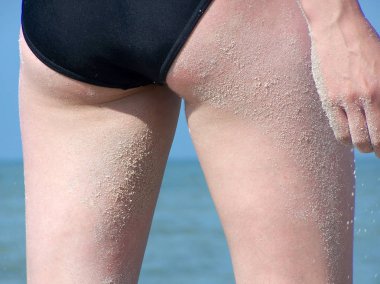 Sahilde kum kadınla örtülü bacaklar.