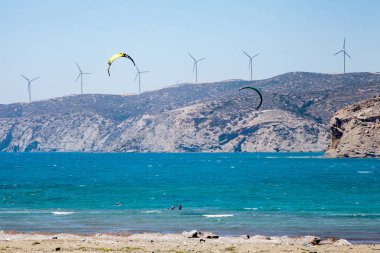Uçurtma alıştırması yapan insanlar. Prasonisi, Rhodes yarımadasındaki plaj. Deniz kıyısında renkli uçurtmalar. Mavi deniz ve rüzgar sörfü.