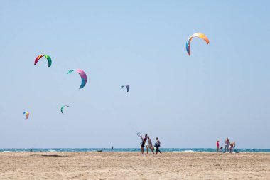 Uçurtma alıştırması yapan insanlar. Prasonisi, Rhodes yarımadasındaki plaj. Deniz kıyısında renkli uçurtmalar. Mavi deniz ve rüzgar sörfü.