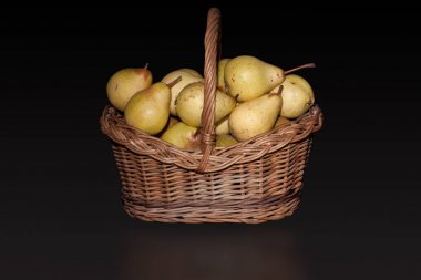 Saf siyah arka plan üzerine armut ile hasır sepet.
