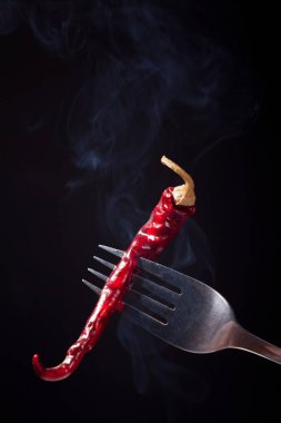 Bir çatal üzerinde Impaled biber. Siyah bir zemin üzerine kırmızı sıcak biber biber. Kurutulmuş biber Impaled. Haşlanmış sebze.