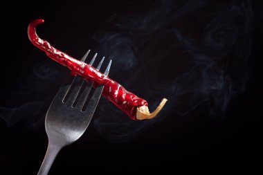 Bir çatal üzerinde Impaled biber. Siyah bir zemin üzerine kırmızı sıcak biber biber. Kurutulmuş biber Impaled. Haşlanmış sebze.