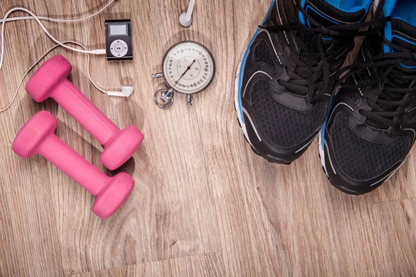 Fitness gym and running equipment. Stopwatch and running shoes, jumping rope and music player. Time for fitness. Sport running accessories on the wooden floor.