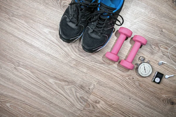 Fitness gym and running equipment. Stopwatch and running shoes, jumping rope and music player. Time for fitness. Sport running accessories on the wooden floor.