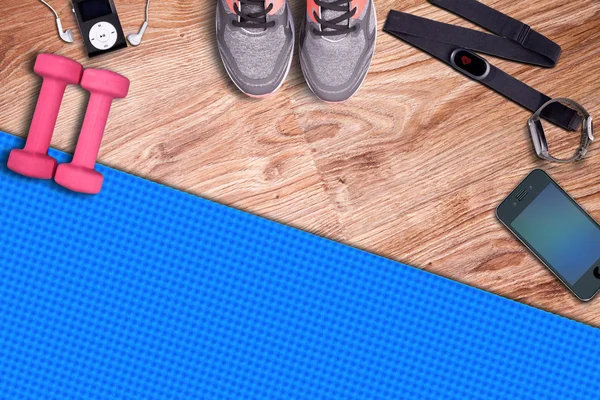 Fitness gym mat and light pink dumbbells. Fit equipment. Smartphone whit heart rate monitor and sensor. Headphones and music player.