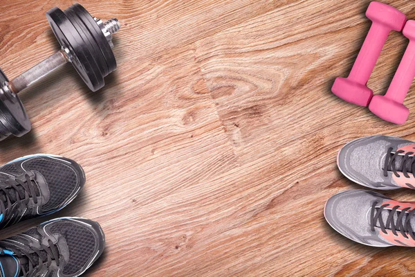 Running shoes and training. The joint training at home with dumbbells. Fitness equipment on wood floor background.