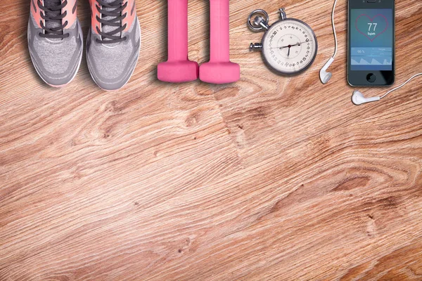 Ekipman çalıştırıyor. Dambıl ve koşu ayakkabıları, analog kronometre ve akıllı telefon. Fitness ve çalışma zamanı. Ahşap zemin üzerinde Spor aksesuarları.